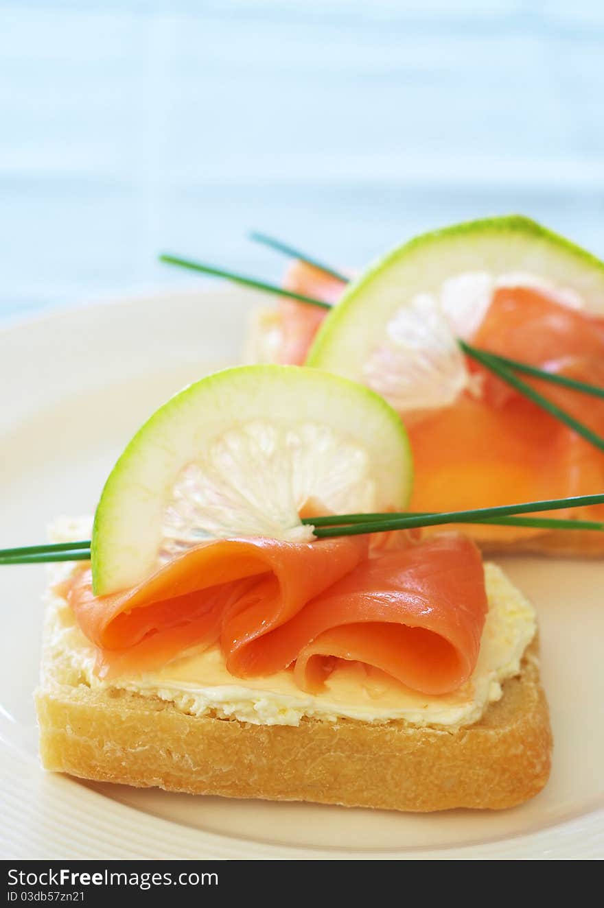 Smoked salmon and cream cheese starter on white bread with slice of lemon and chives. Smoked salmon and cream cheese starter on white bread with slice of lemon and chives