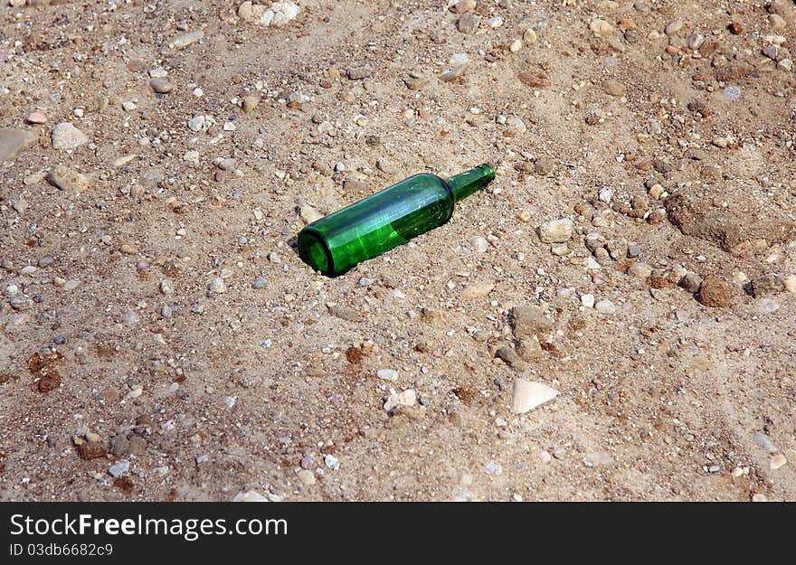 Lone green empty bottle left in the sand. Lone green empty bottle left in the sand