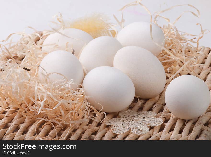 Seven white eggs lying on straw base