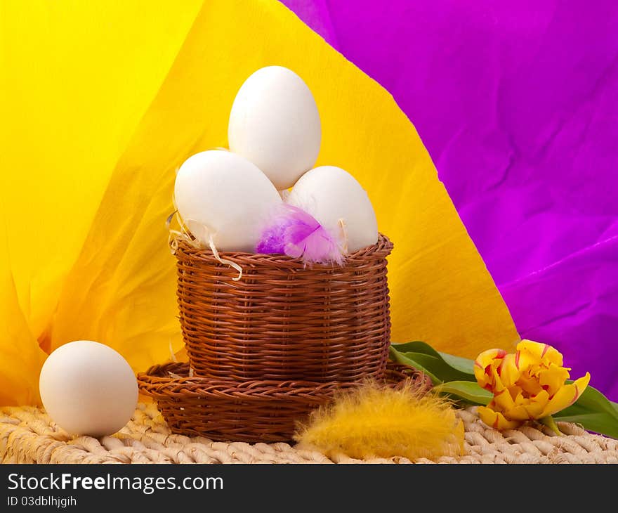 Eggs in straw basket with yellow and purple background on tray