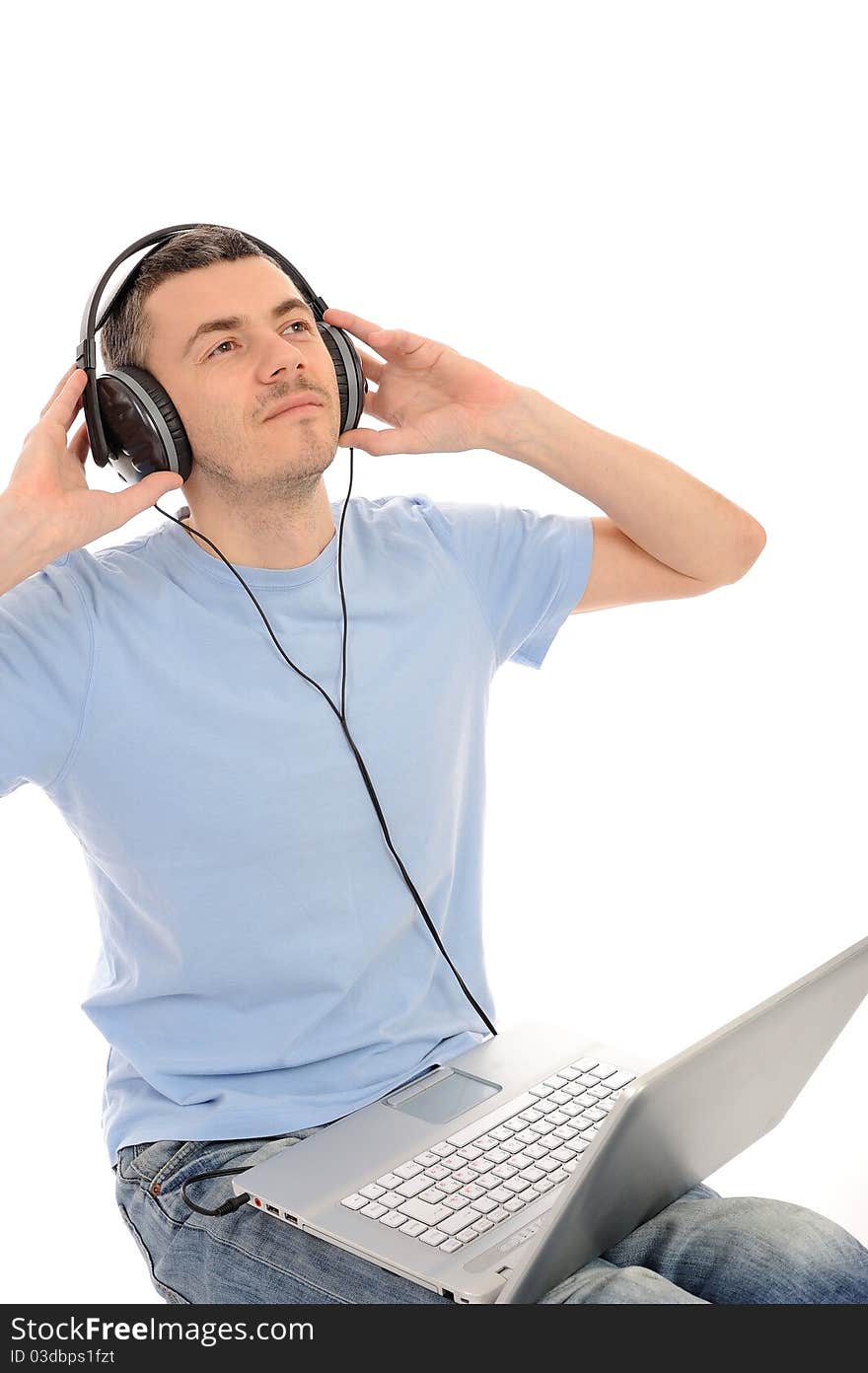 Young handsome man listening to music in headphones from computer. isolated. Young handsome man listening to music in headphones from computer. isolated