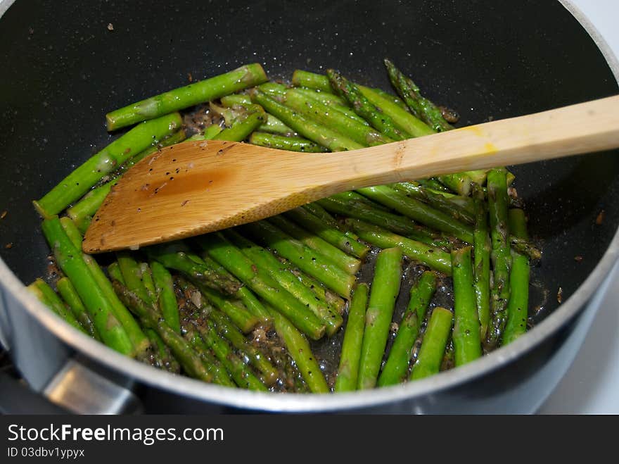 Asparagus being cooked in a pot with spices and bamboo utensil. Asparagus being cooked in a pot with spices and bamboo utensil