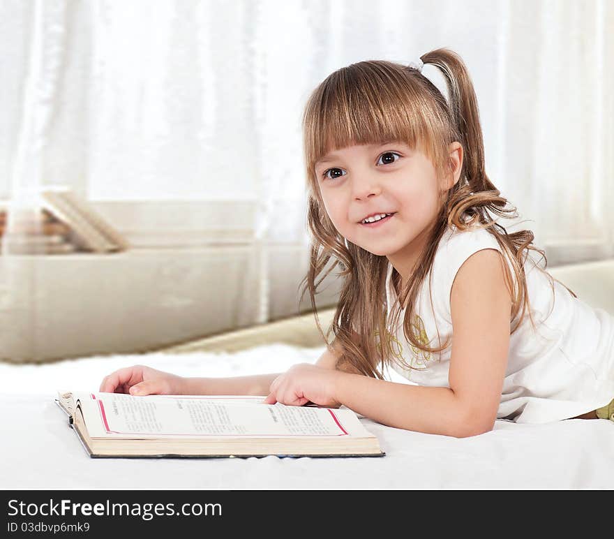 Lovely little girl, reading a book, on the bed. Lovely little girl, reading a book, on the bed