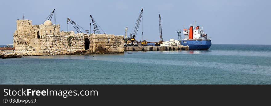 Tower cranes and boats in back of an ancient sea castle. Tower cranes and boats in back of an ancient sea castle