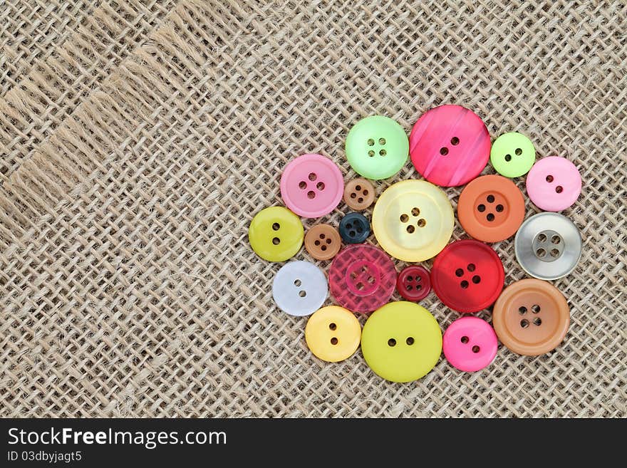 Colorful buttons on burlap background