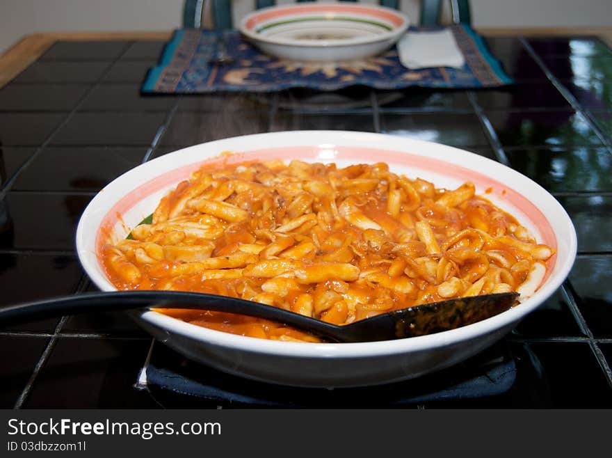 Cavatelli with an Italian Calamari Sauce in a serving dish on a black tile table. Cavatelli with an Italian Calamari Sauce in a serving dish on a black tile table.