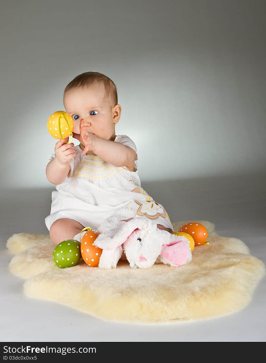 Young babay girl sitting and playing with easter egg. Very cute baby. Young babay girl sitting and playing with easter egg. Very cute baby.