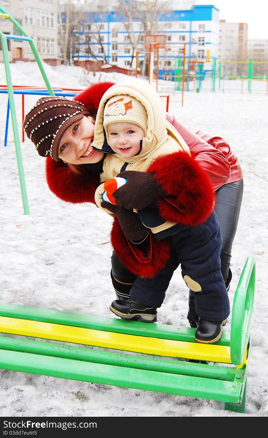 Mother and baby on the playground in winter. Mother and baby on the playground in winter