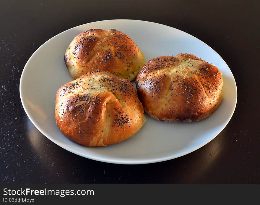 Three poppy seeds shortbread cakes on white plate, on top of black table