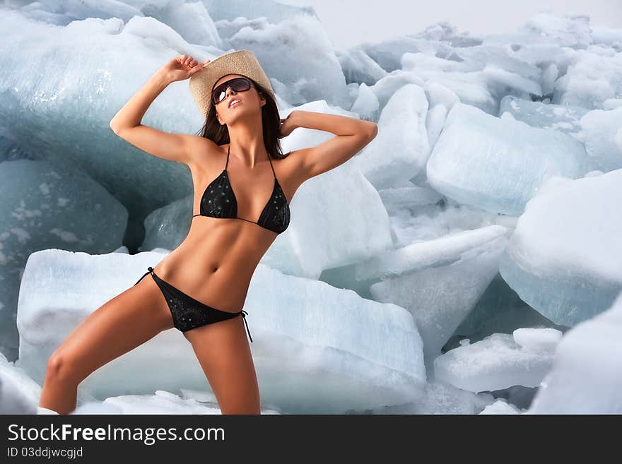 A studio portrait of a nude woman in bikini posing against the background of ice blocks. A studio portrait of a nude woman in bikini posing against the background of ice blocks.