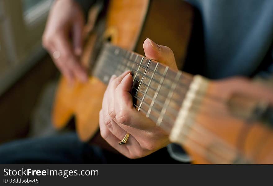 Brown guitar in hands of the guy playing it