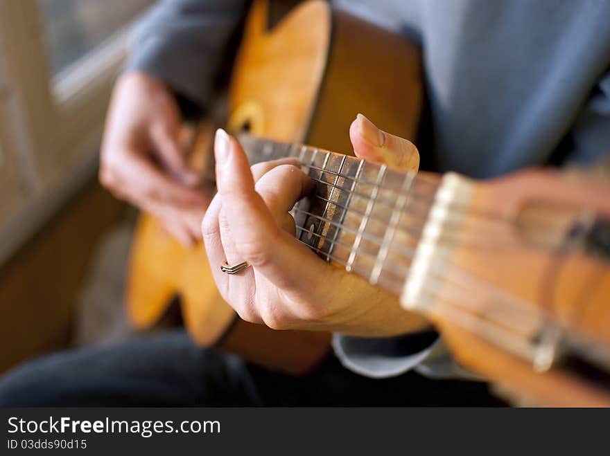 Brown guitar in hands of the guy playing it