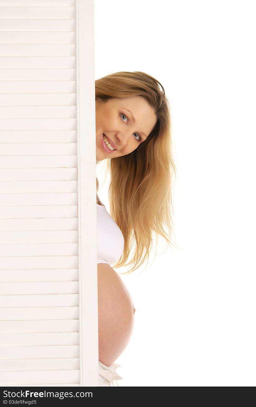 Pregnant woman peeping from behind the door isolated on white