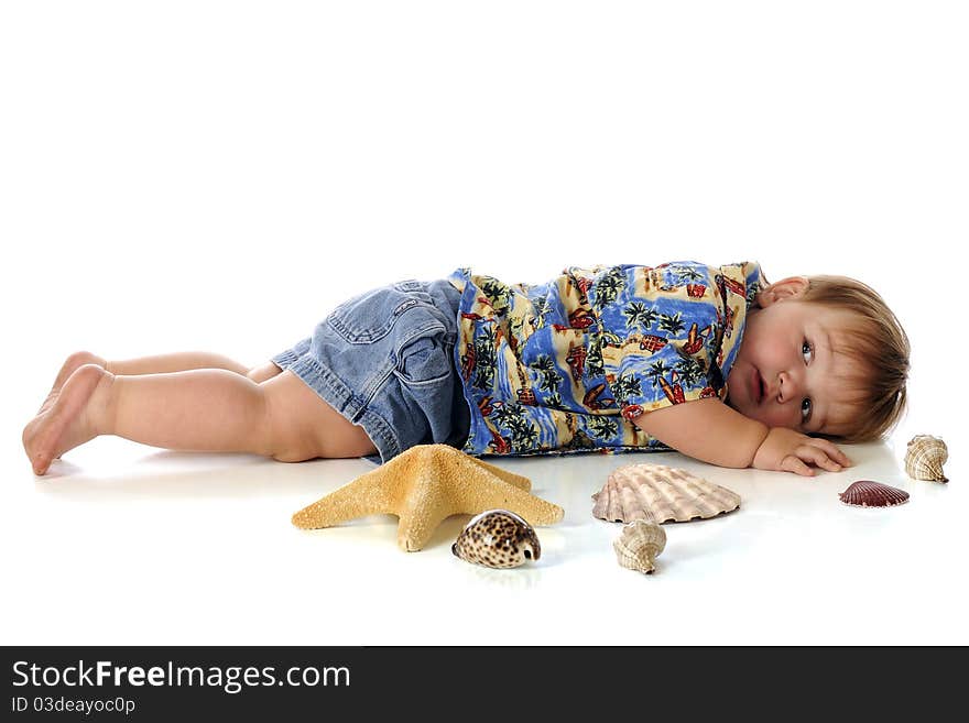 A chubby baby boy in a Hawaiian shirt and shorts, laying flat-out on his belly among sea shells. Isolated on white. A chubby baby boy in a Hawaiian shirt and shorts, laying flat-out on his belly among sea shells. Isolated on white.