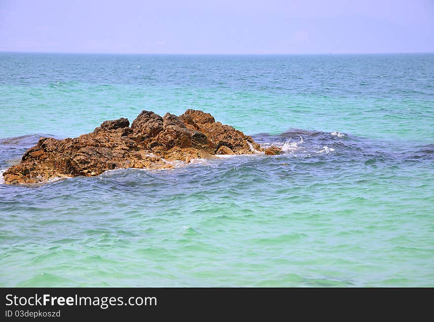 Small rock stand lonely among sea water, shown as color comparing between sea water and stone. Small rock stand lonely among sea water, shown as color comparing between sea water and stone.