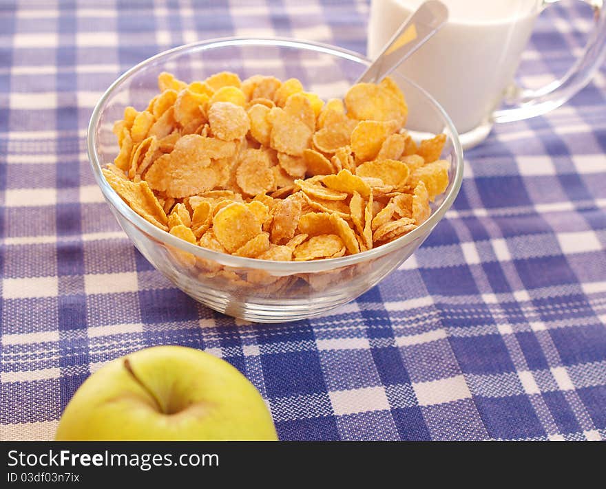 Cornflakes and milk on the table out of the blue tablecloth. Light breakfast.