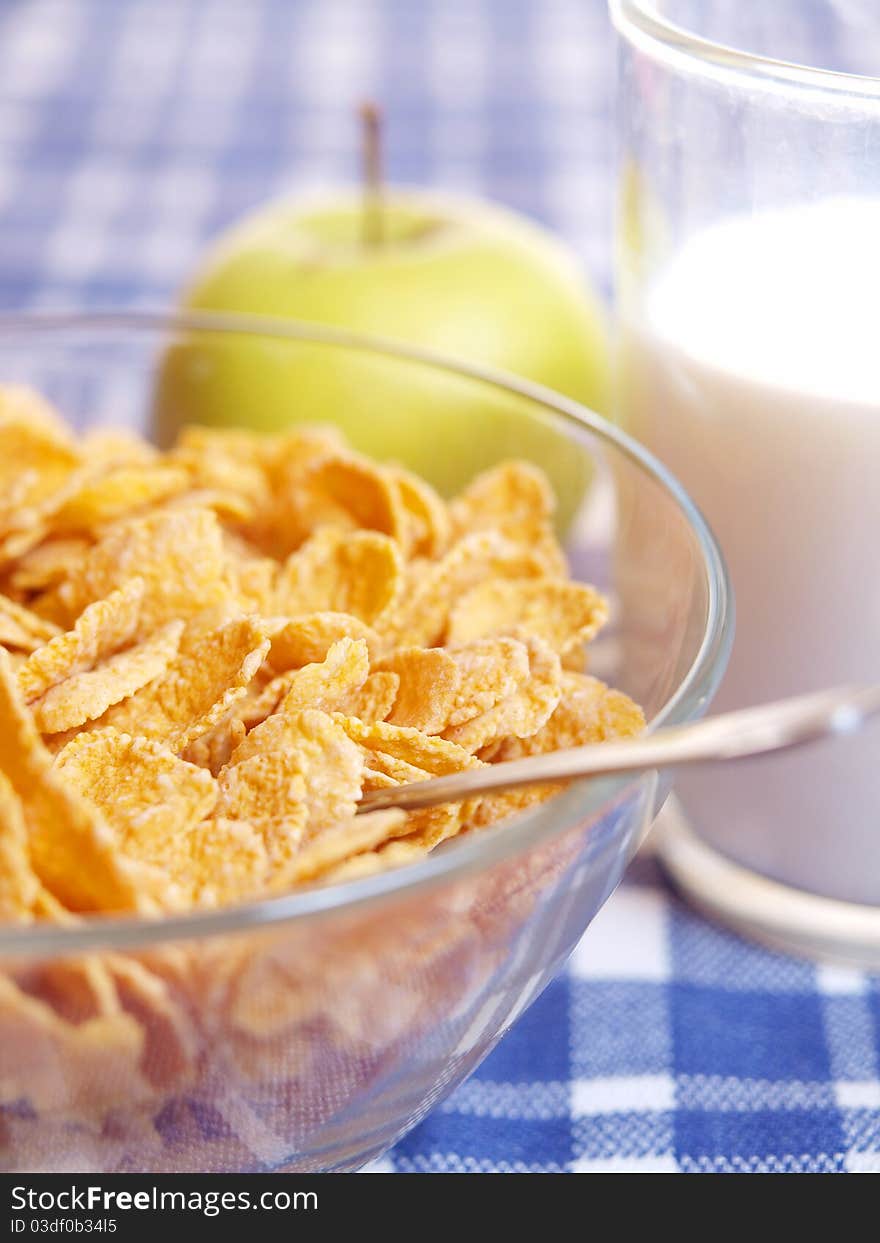 Cornflakes and milk on the table out of the blue tablecloth. Light breakfast.