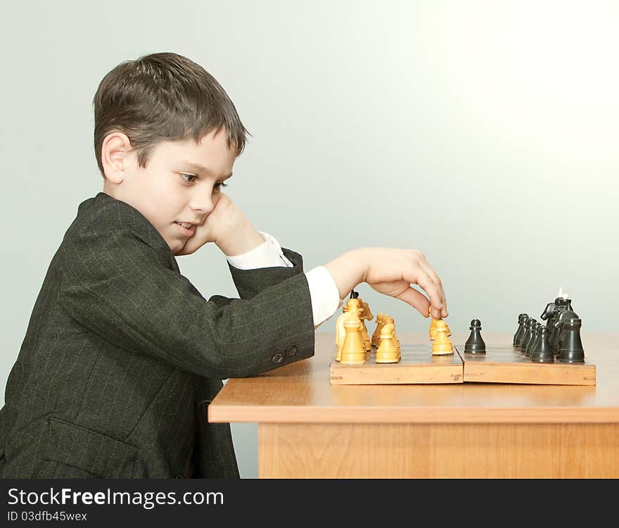 The boy plays chess in a suit. The boy plays chess in a suit