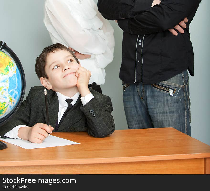 The schoolboy sits at a school desk and dreams