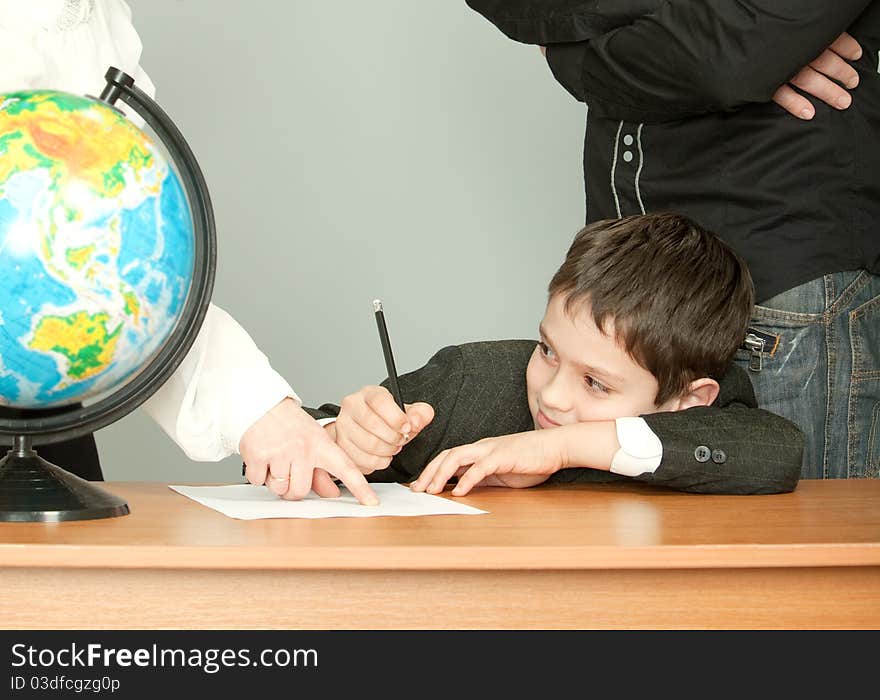 The schoolboy sits at a school desk and dreams