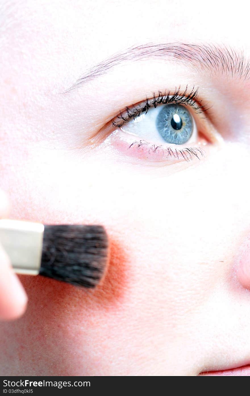 A woman using red powder on her face. A woman using red powder on her face