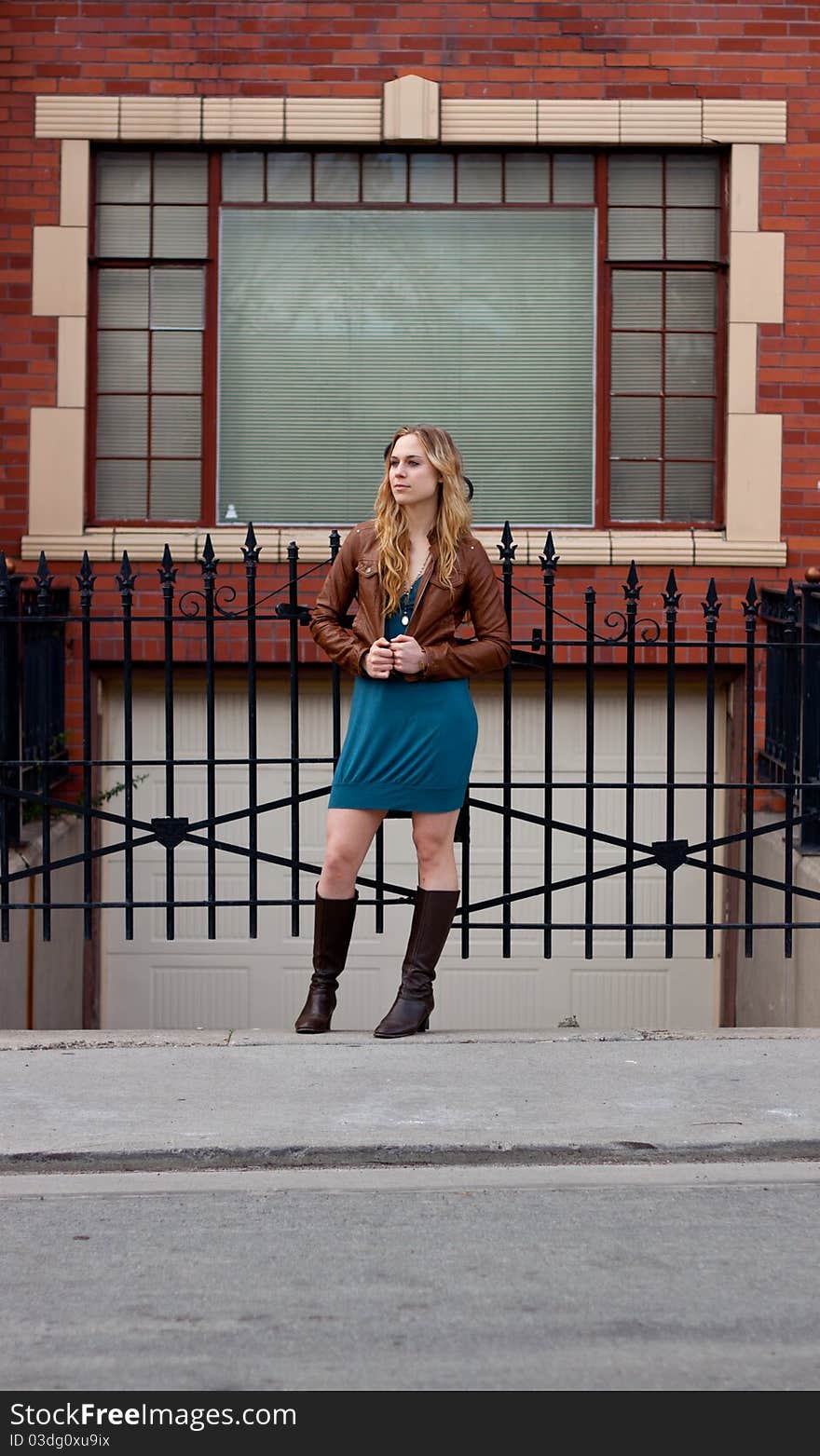 A girl stands in front of an iron gate. A girl stands in front of an iron gate.