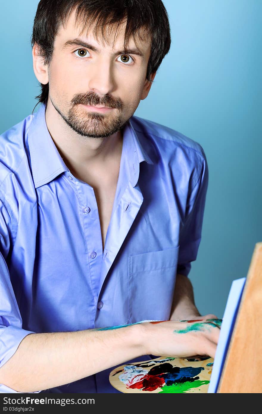 Portrait of an artist painting on easel. Shot in a studio.