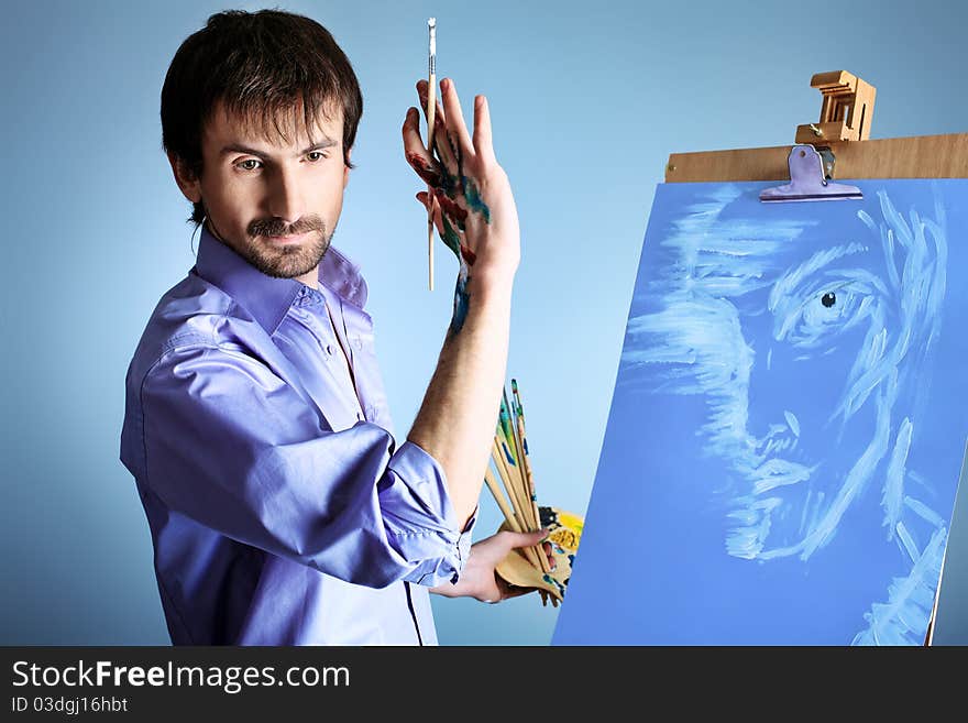 Portrait of an artist painting on easel. Shot in a studio. Portrait of an artist painting on easel. Shot in a studio.