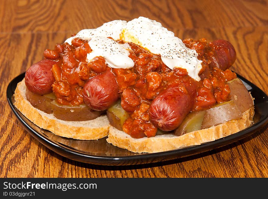 Three Chili dogs on top of potatoes and bread, covered in Sour Cream, Hot Sauce and Pepper. Three Chili dogs on top of potatoes and bread, covered in Sour Cream, Hot Sauce and Pepper