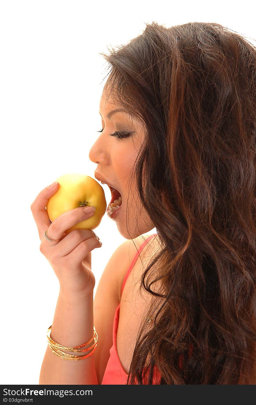 A young Asian woman eating a yellow apple, with her long curly
brunette hair, over white backgroynd. A young Asian woman eating a yellow apple, with her long curly
brunette hair, over white backgroynd.