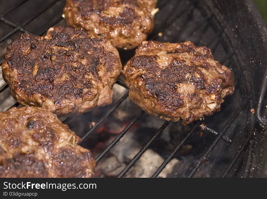 Burgers cooking on barbecue grill over charcoal