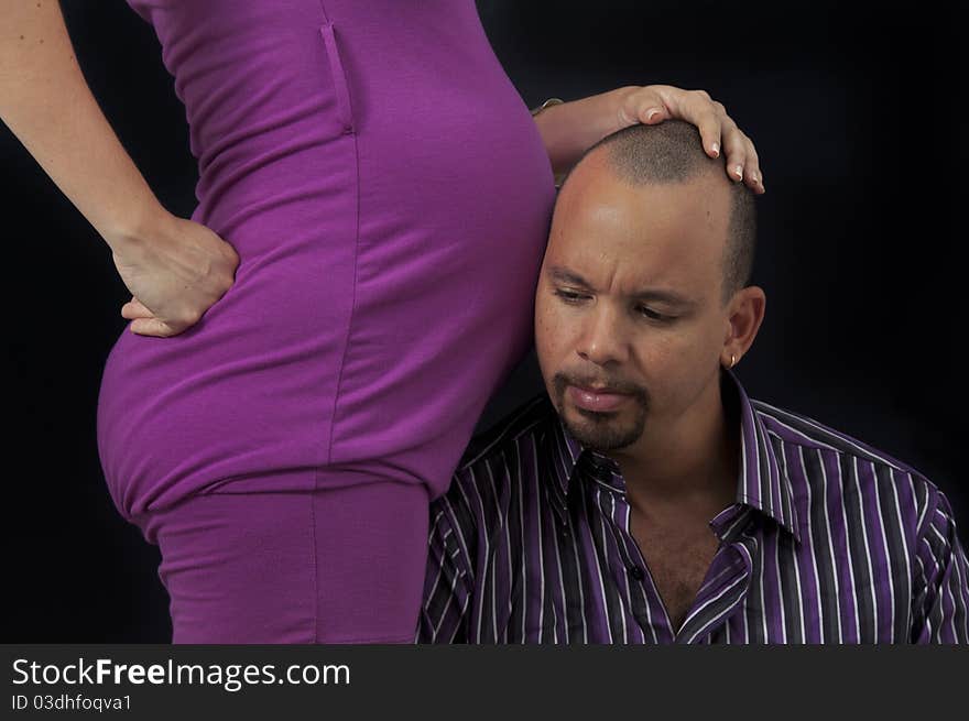 Portrait of young cheerful hispanic couple specting a child, isolated on black. Portrait of young cheerful hispanic couple specting a child, isolated on black