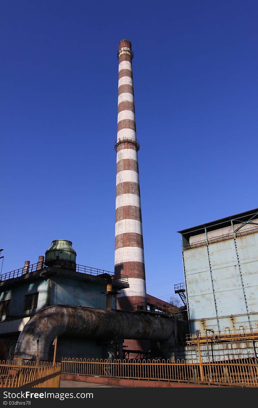 Disused steel plant chimney with blue sky