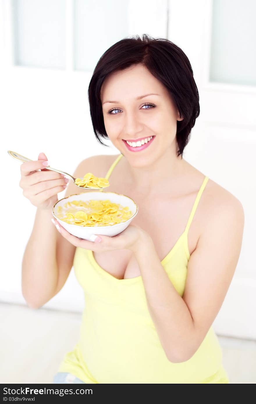 Girl eating cornflakes on a light background