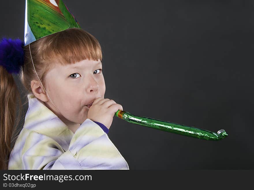 Horizontal view of little girl playfully blowing noisemakers a birthday party. Horizontal view of little girl playfully blowing noisemakers a birthday party