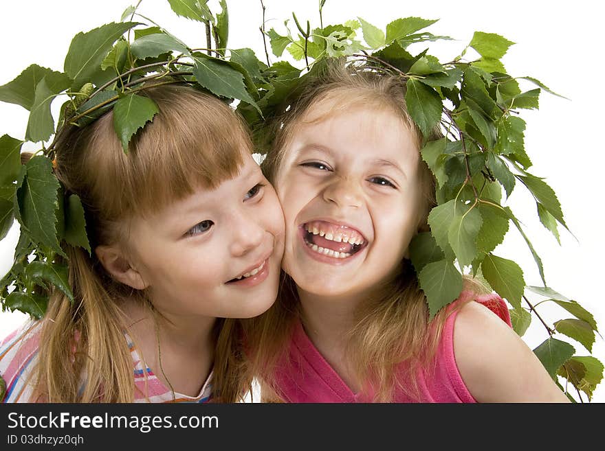 Cheerful little girl with a wreath on a head from birch leaves on a gray background. Cheerful little girl with a wreath on a head from birch leaves on a gray background