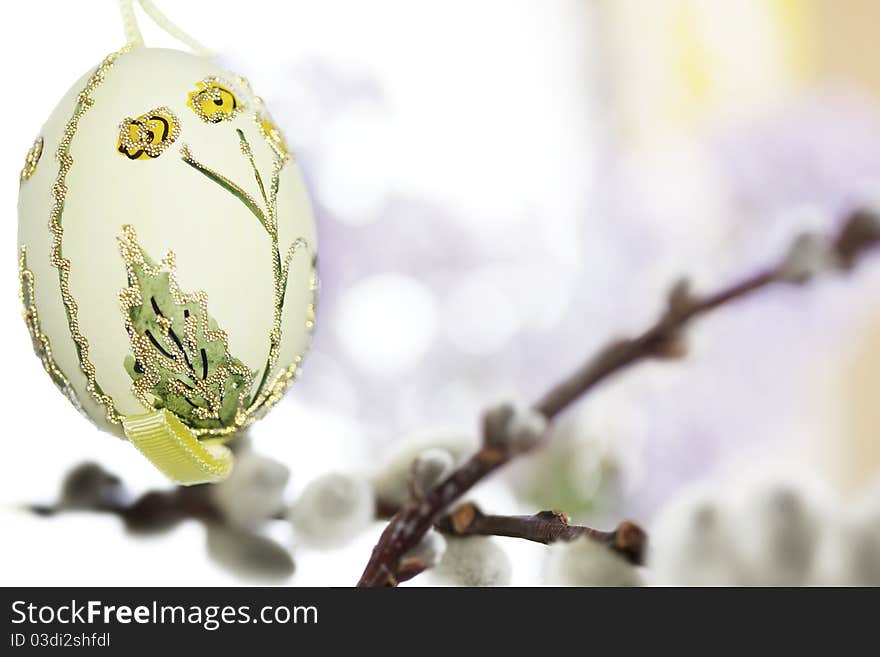 Painted yellow easter egg hanging on catkin branch with purple flowers in background. Painted yellow easter egg hanging on catkin branch with purple flowers in background.