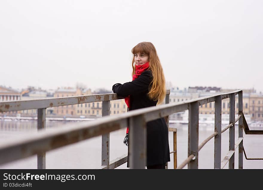 Young girl in the red scarf and black coat standing on iron bridge. Young girl in the red scarf and black coat standing on iron bridge