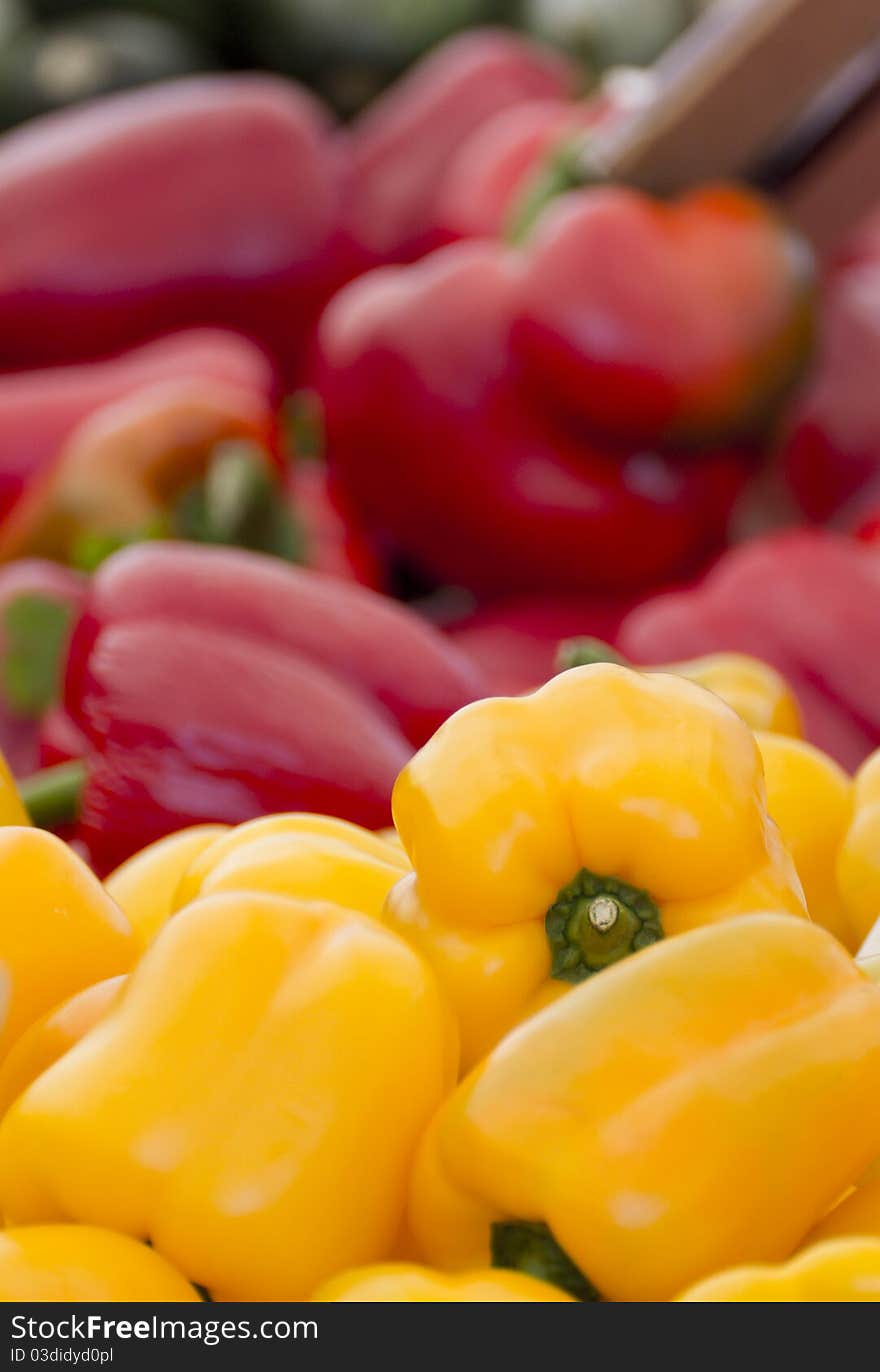 Yellow Peppers and Red Peppers sitting on a street market's table.