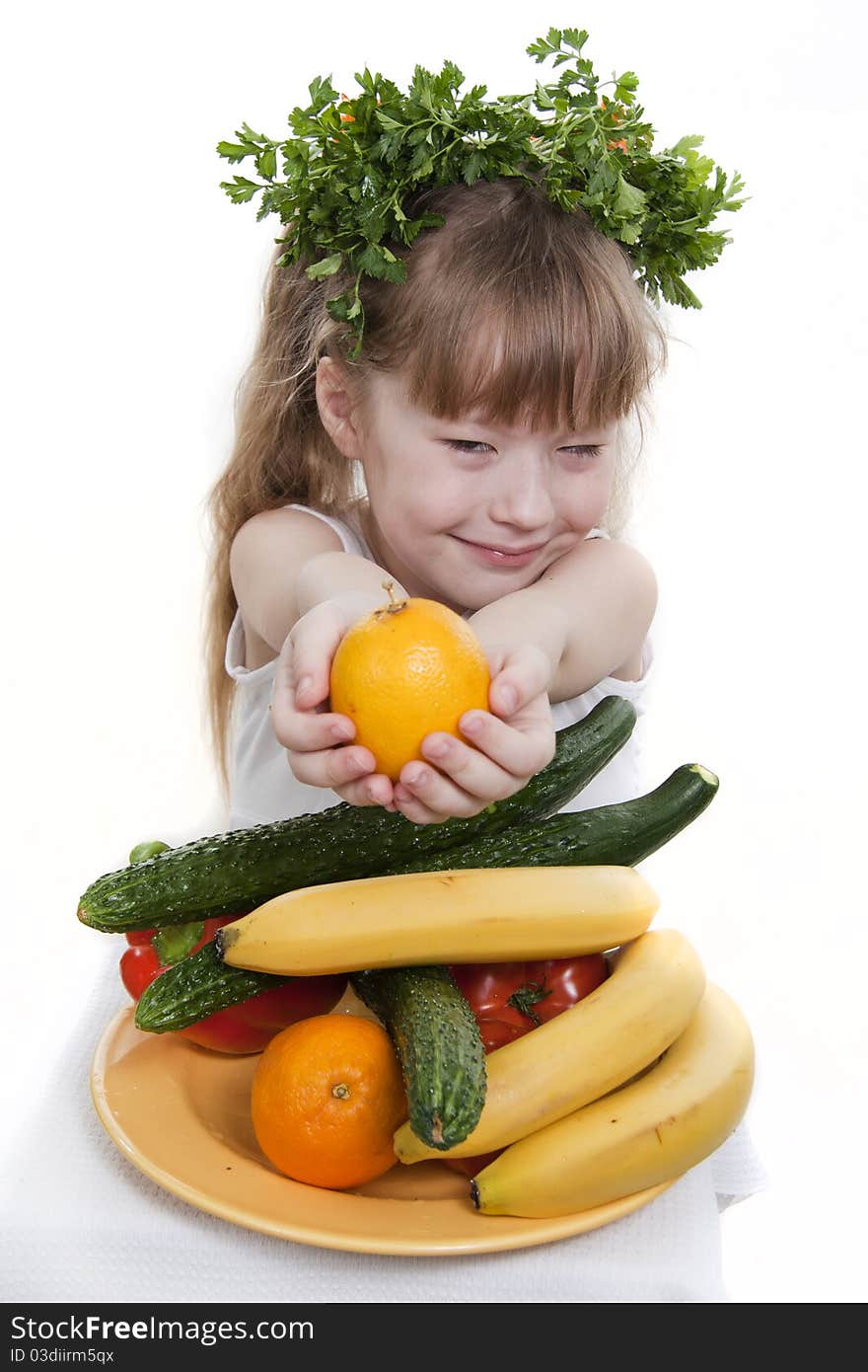 Child holds vegetables and fruit.