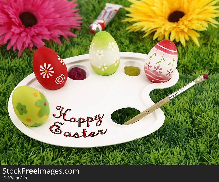 Spring flowers and colorful Easter eggs on palette over grass. Spring flowers and colorful Easter eggs on palette over grass