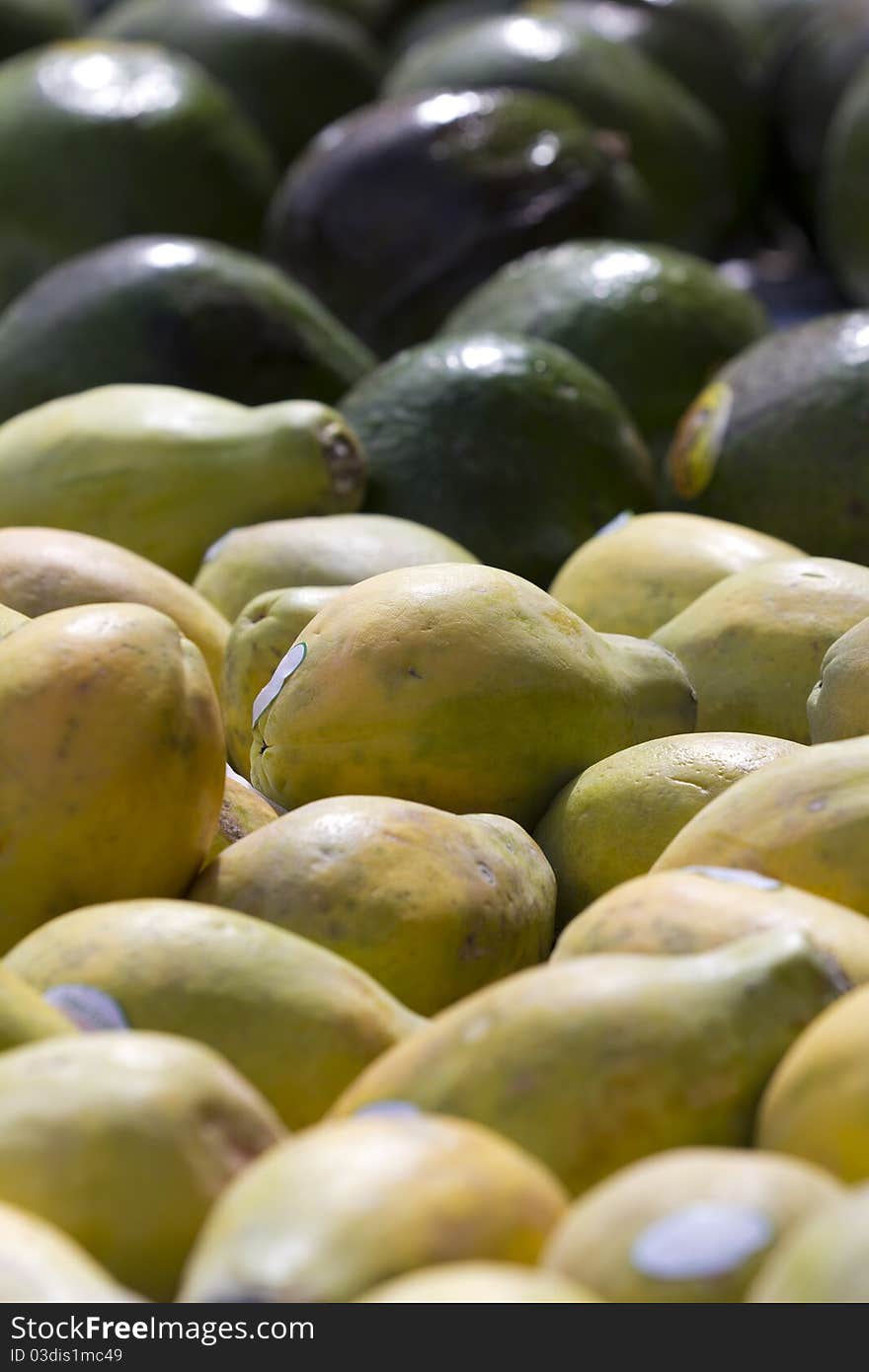 Close up on some papayas and avocados on the background.