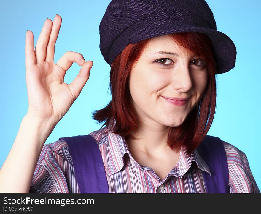 Beautiful girl in shirt and violet cap show OK