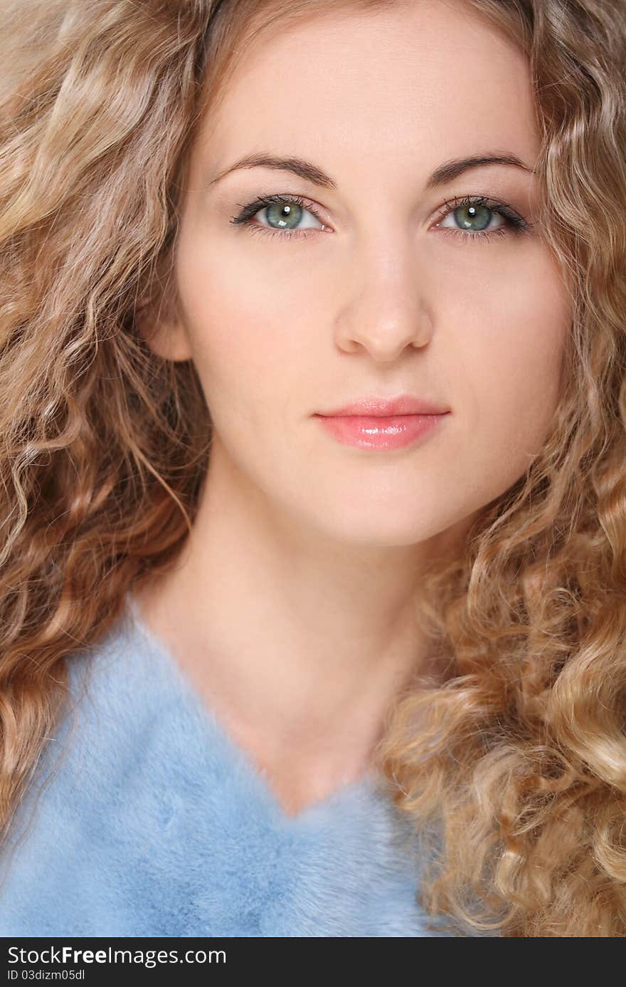 Portrait of the beauty young blond girl with curly hair in blue