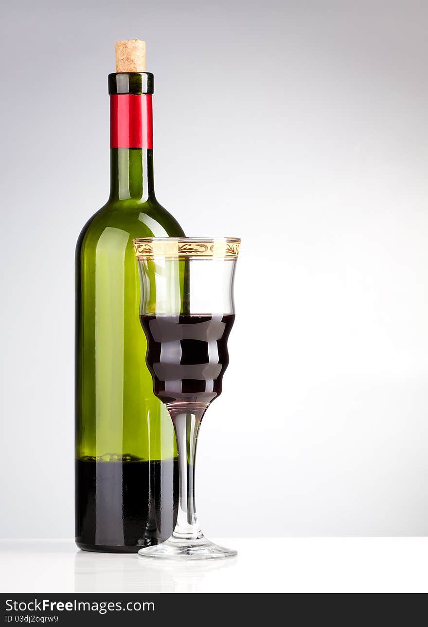 Wine bottle and wineglass on a grey background