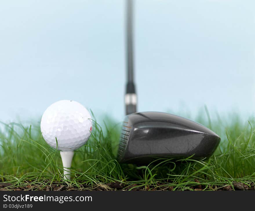 A golf ball on green grass siolated against a blue sky. A golf ball on green grass siolated against a blue sky