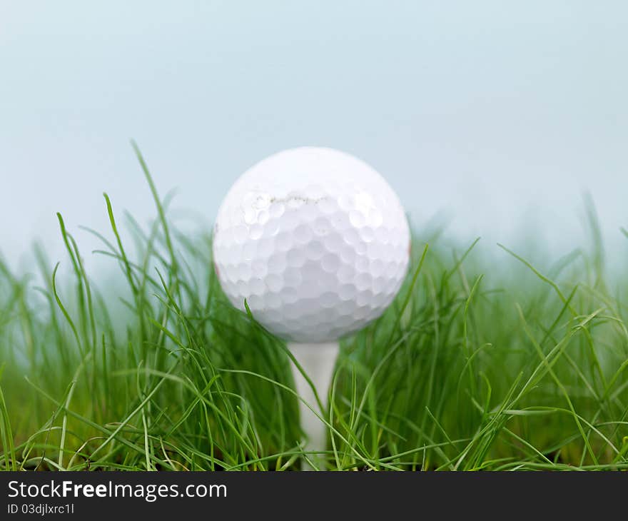 A golf ball on green grass siolated against a blue sky. A golf ball on green grass siolated against a blue sky