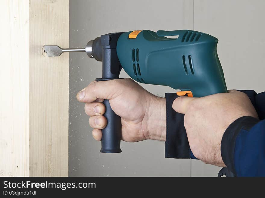 A man drilling a hole in wooden block. A man drilling a hole in wooden block