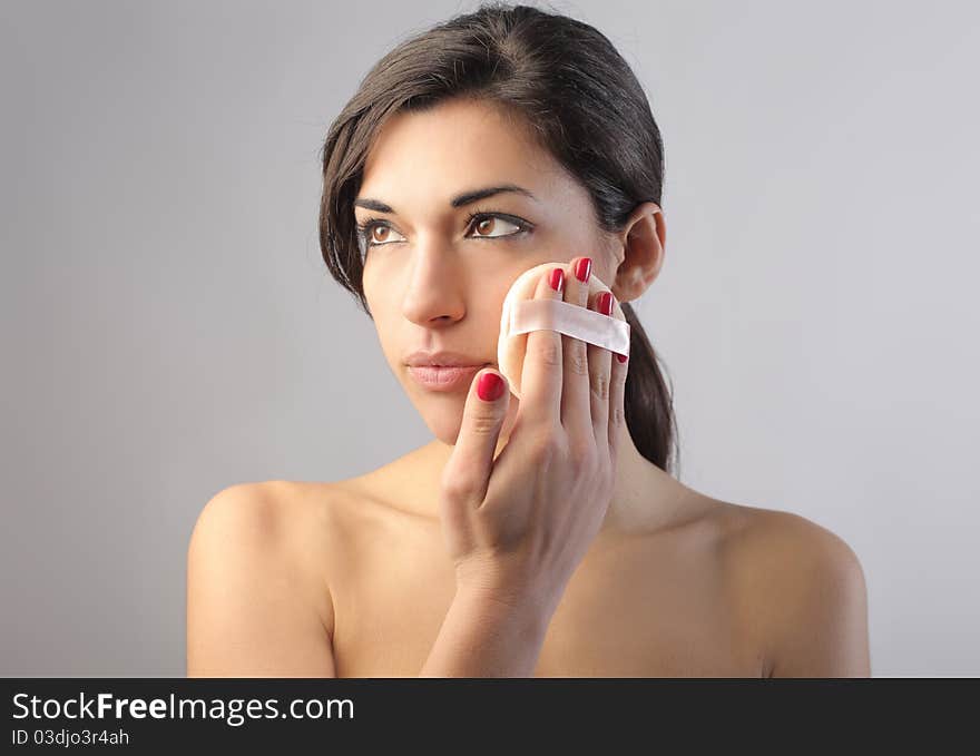 Beautiful woman putting on some foundation cream. Beautiful woman putting on some foundation cream