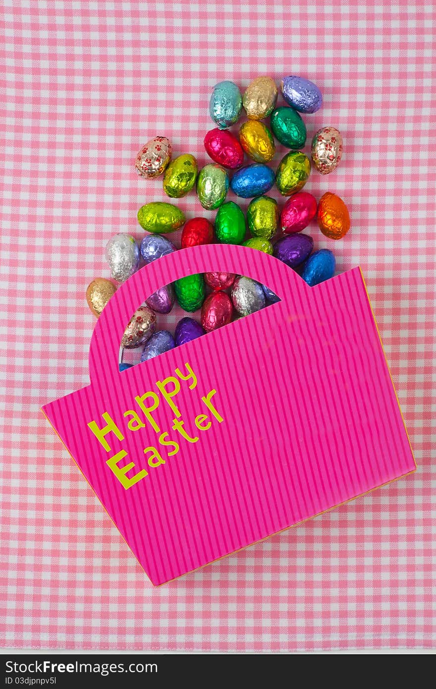 Chocolate Easter eggs falling from a pink bag isolated on a pink background